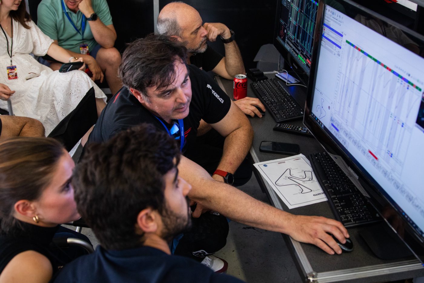 Engineers and drivers reviewing telemetry traces on screen in a race paddock